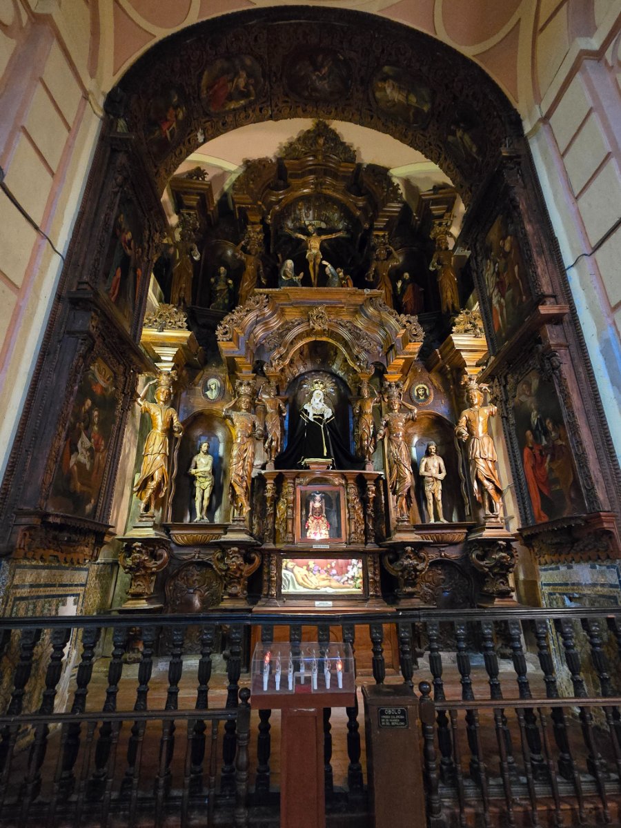 An intricately carved, gilded altar inside a church, featuring religious figures and a central statue, showcasing detailed craftsmanship.