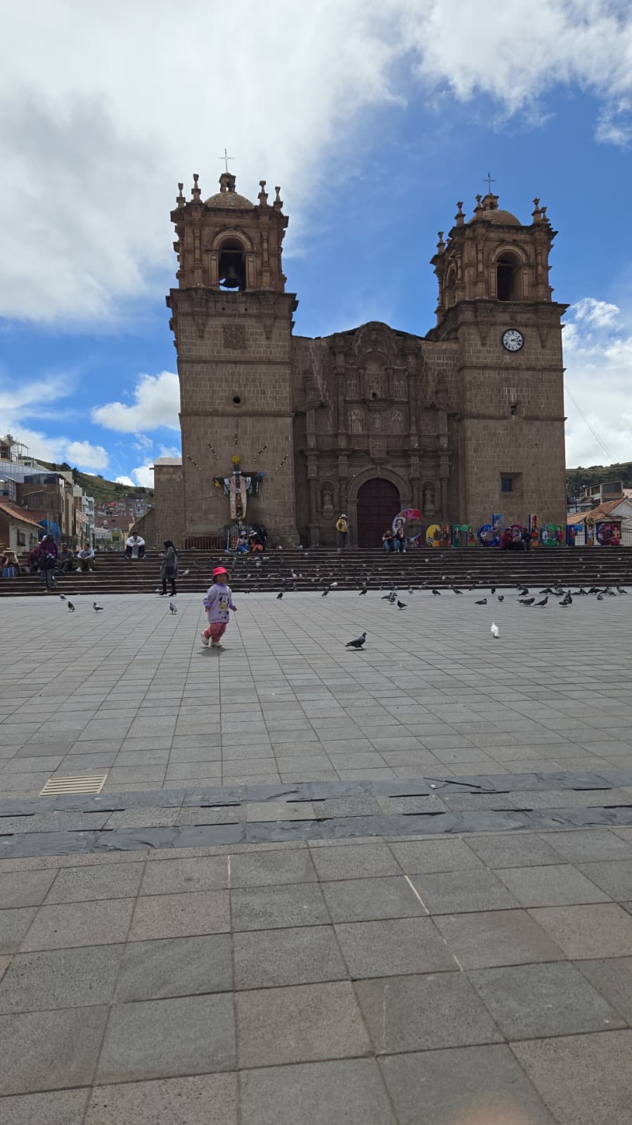 Cathedral facade with twin bell towers, child chasing pigeons in the plaza
