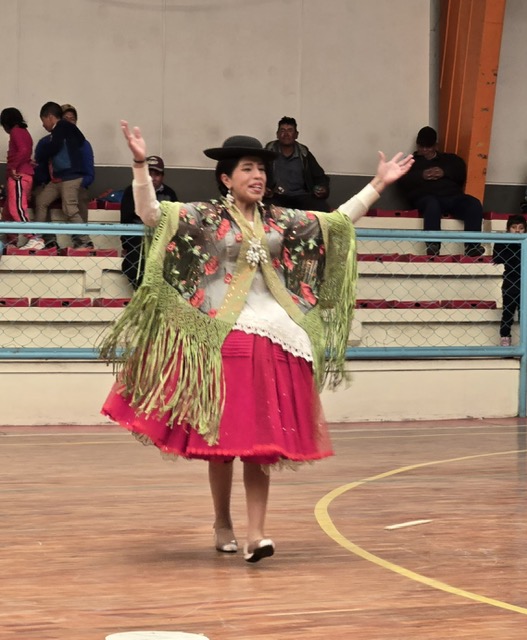 Cholita wrestler performing in full traditional Bolivian attire with bowler hat