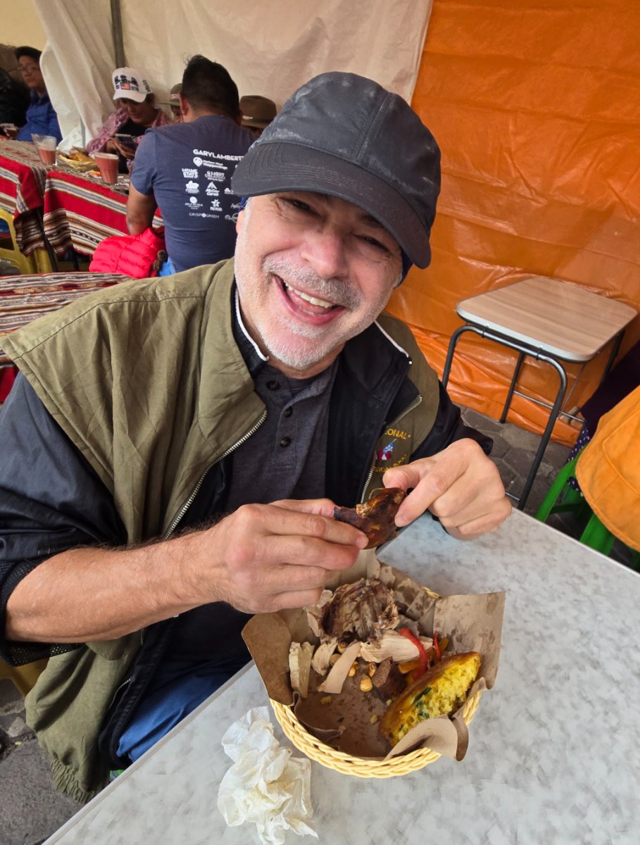 The author smiling and eating a traditional dish at the festival